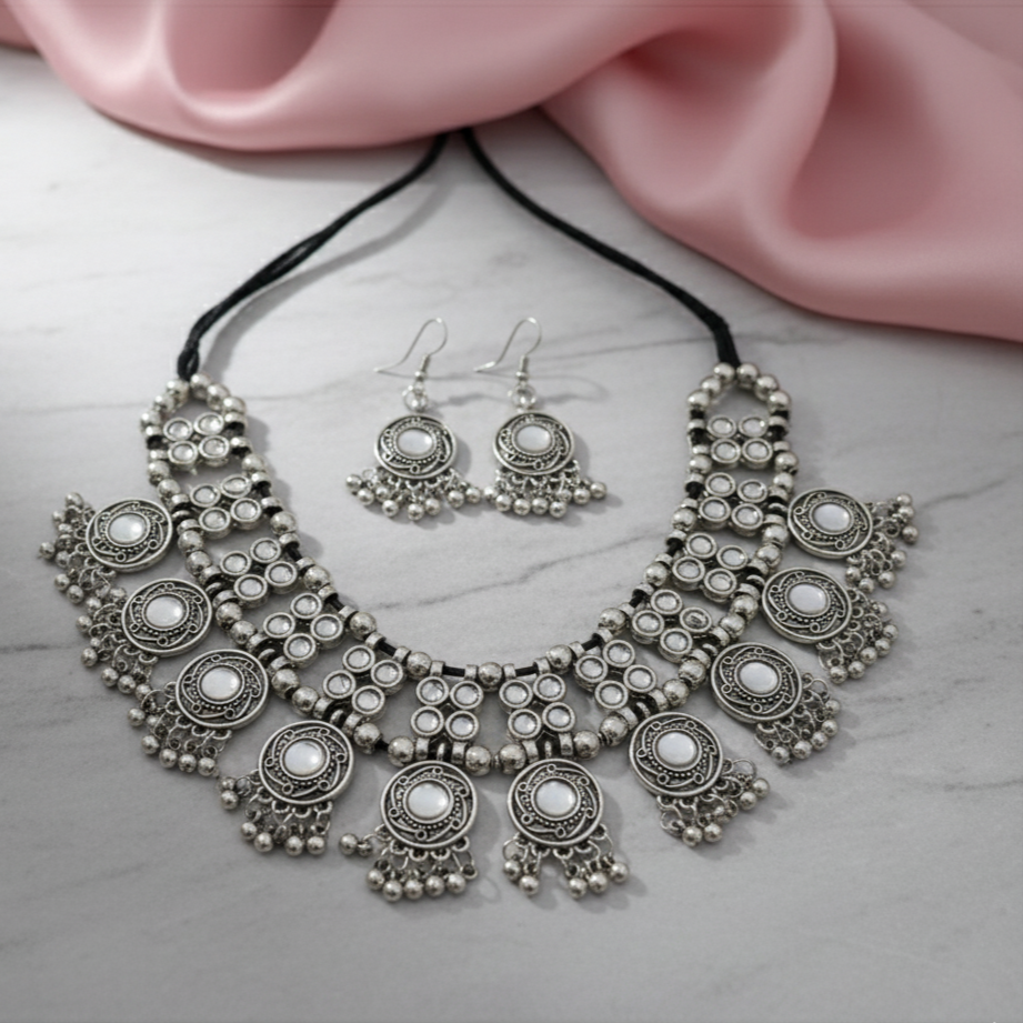 Ethnic oxidized jewelry set with necklace and earrings on a marble surface.